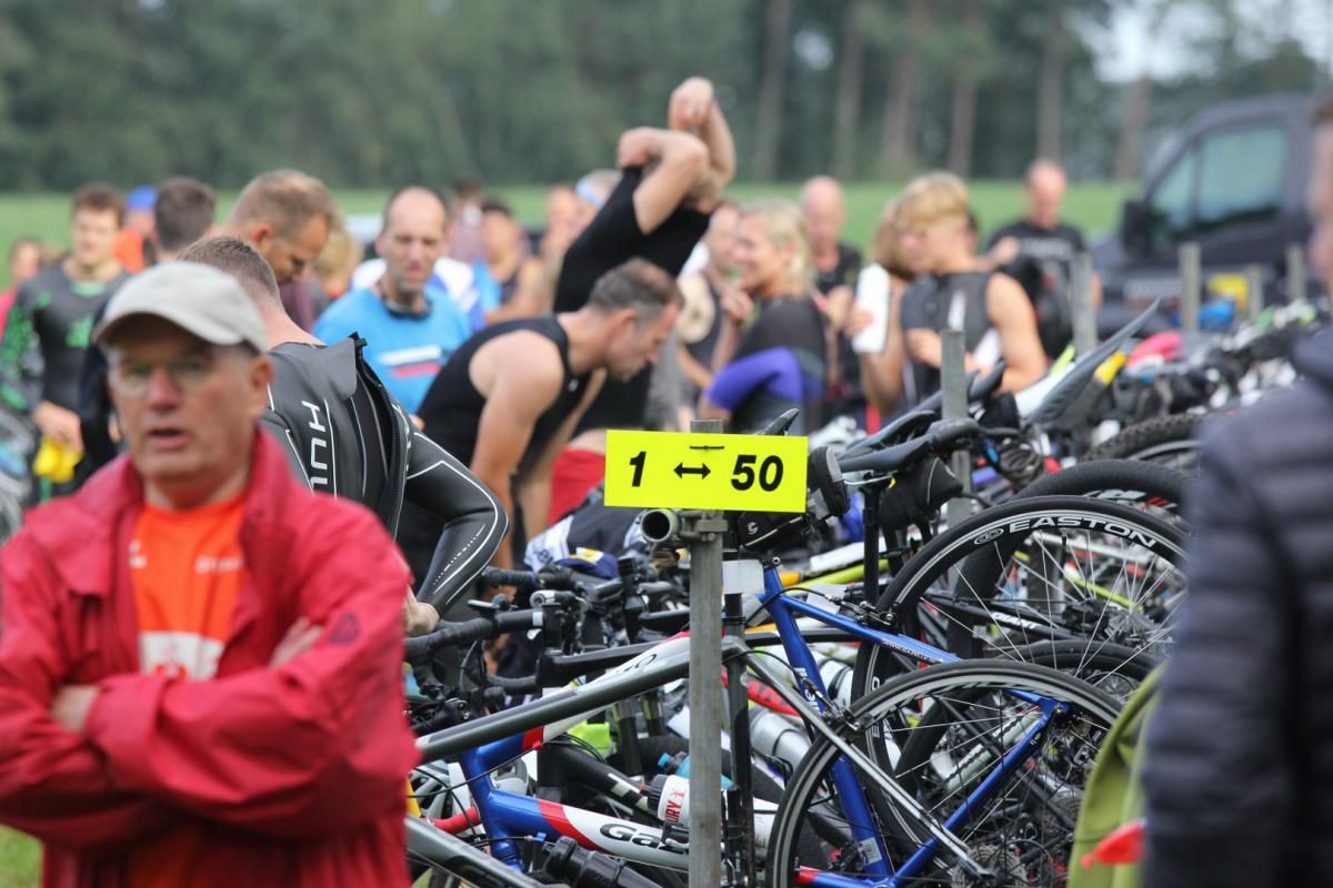Een man staat voor een rij fietsen met een geel bord waarop staat 1-50