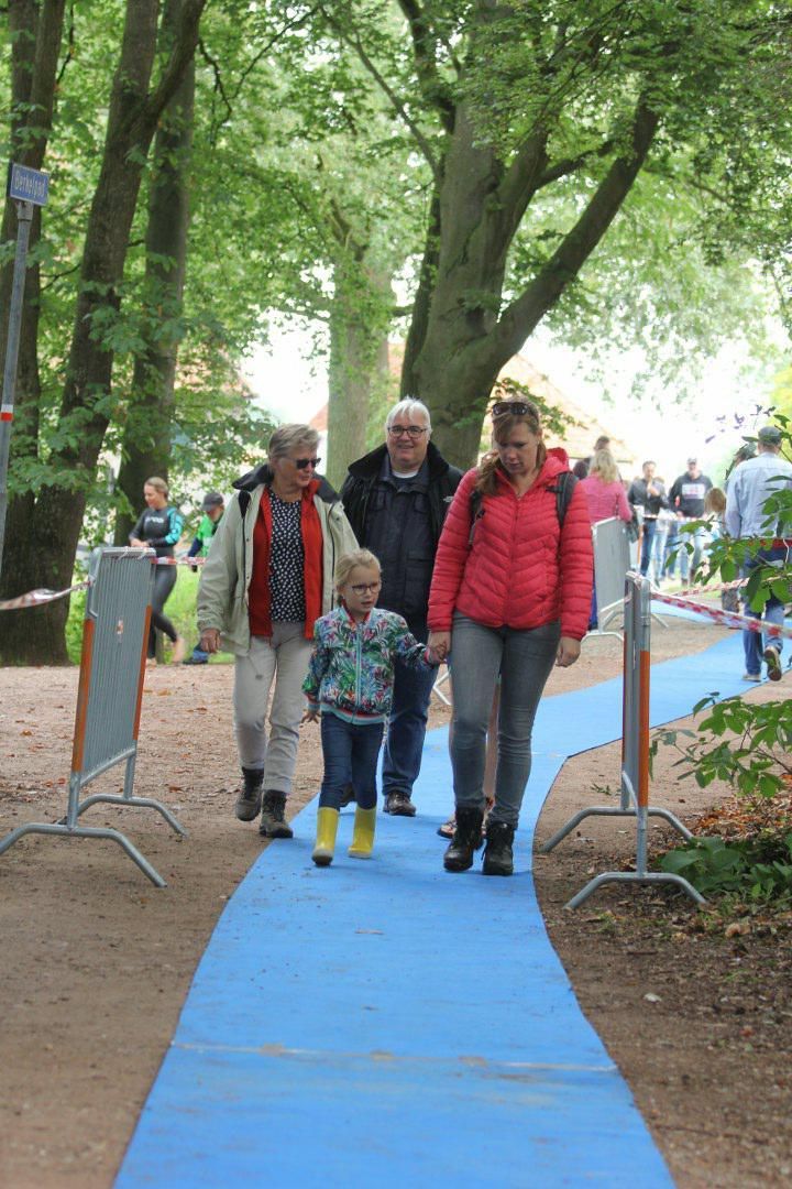 Een groep mensen loopt over een blauwe loper.