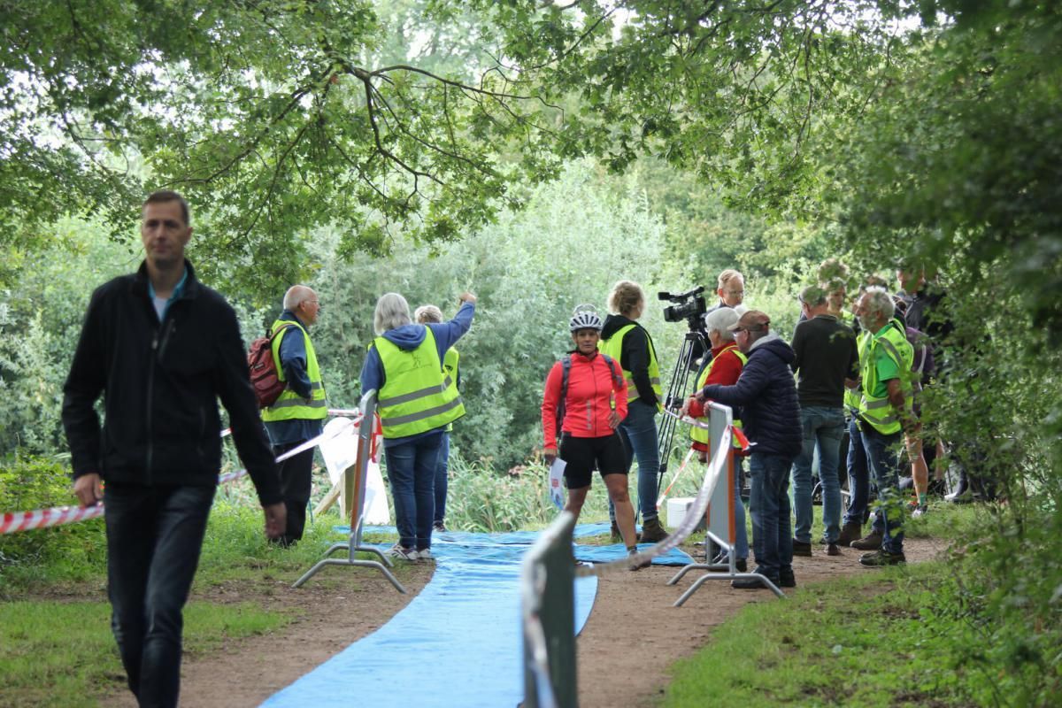 Een groep mensen loopt over een pad in het bos.