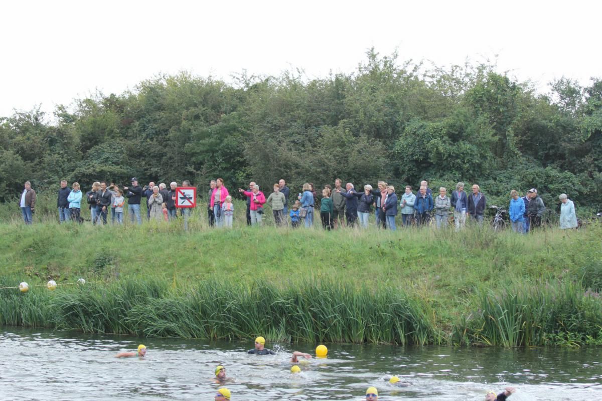 Een groep mensen staat op een met gras begroeide heuvel met uitzicht op een watermassa.
