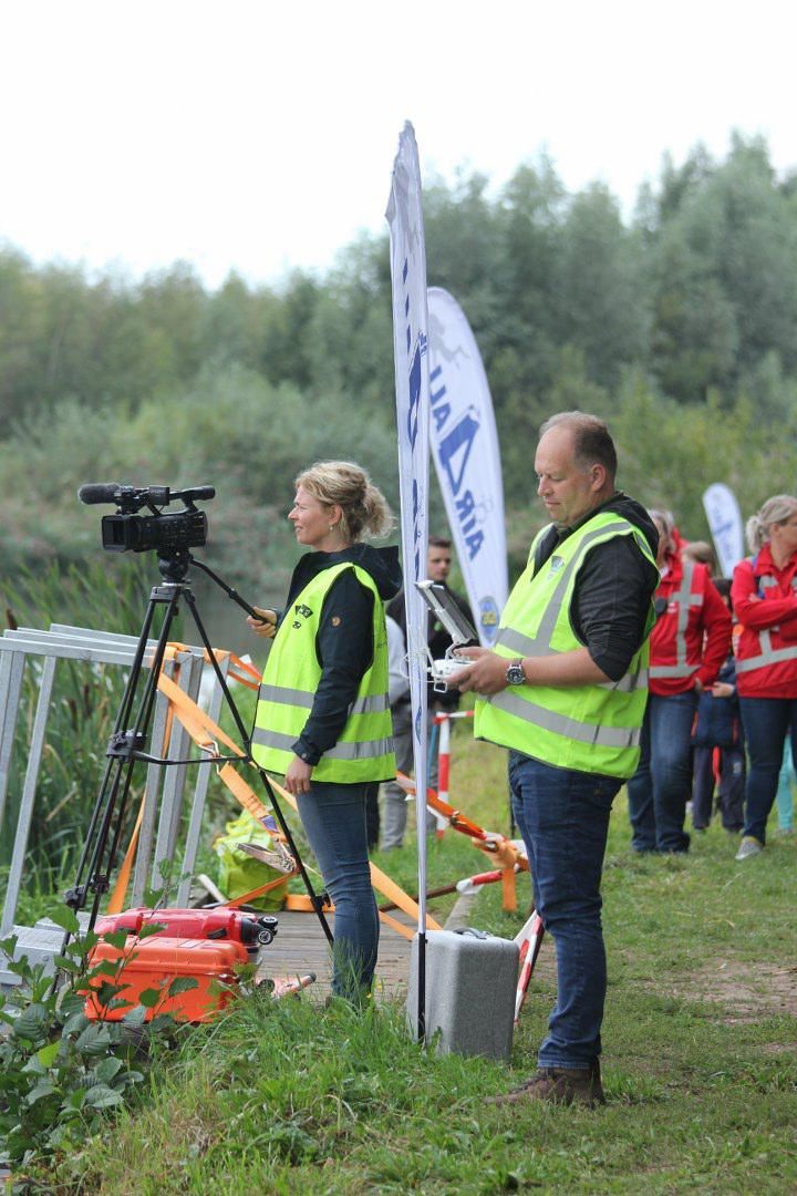 Een man en een vrouw staan ​​in een veld met een camera.
