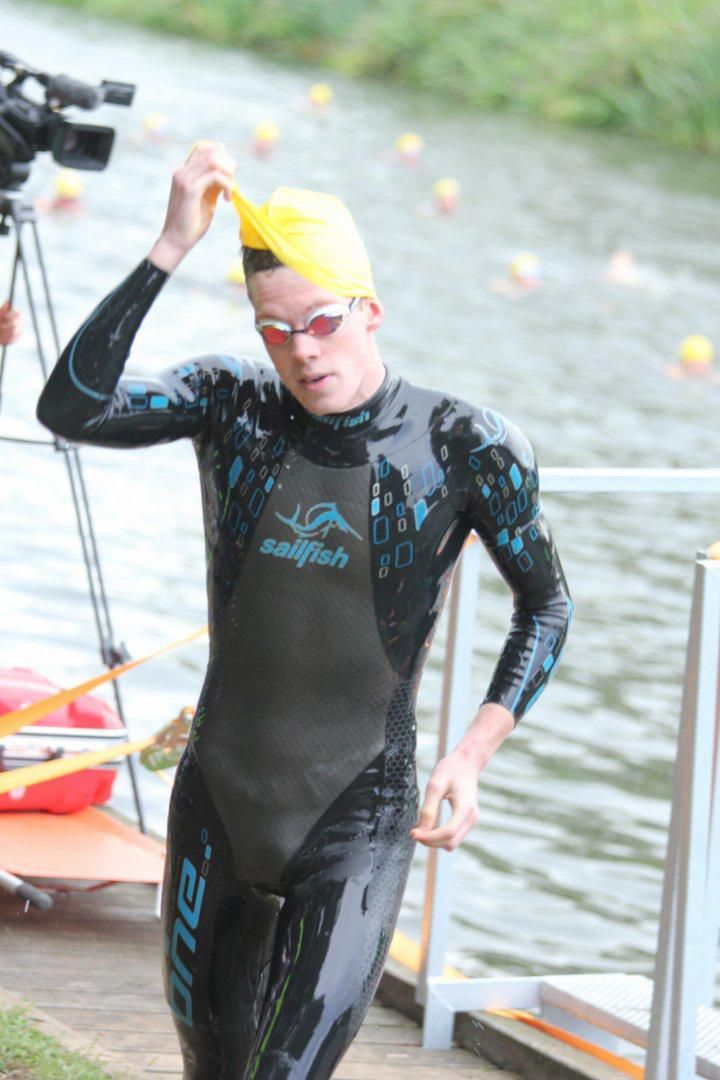 Een man in een wetsuit maakt zich klaar om in het water te gaan zwemmen.