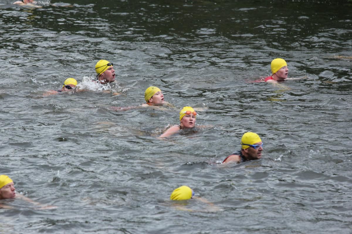 Een groep mensen zwemt in een rivier, met gele badmutsen op.