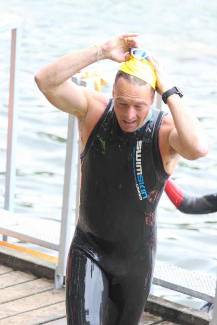 Een man in een wetsuit zet een badmuts op.