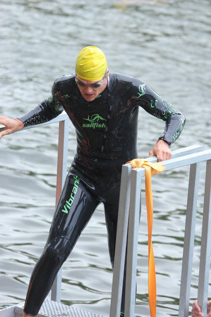 Een man in een wetsuit komt uit het water