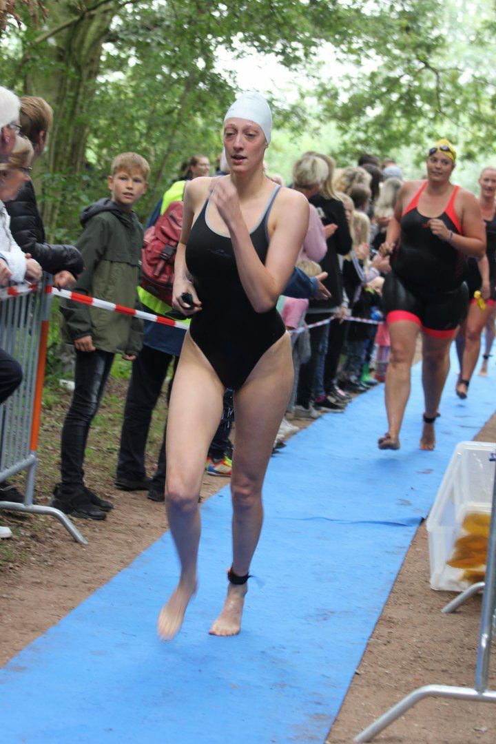 Een vrouw in een zwart badpak rent op een blauwe mat.