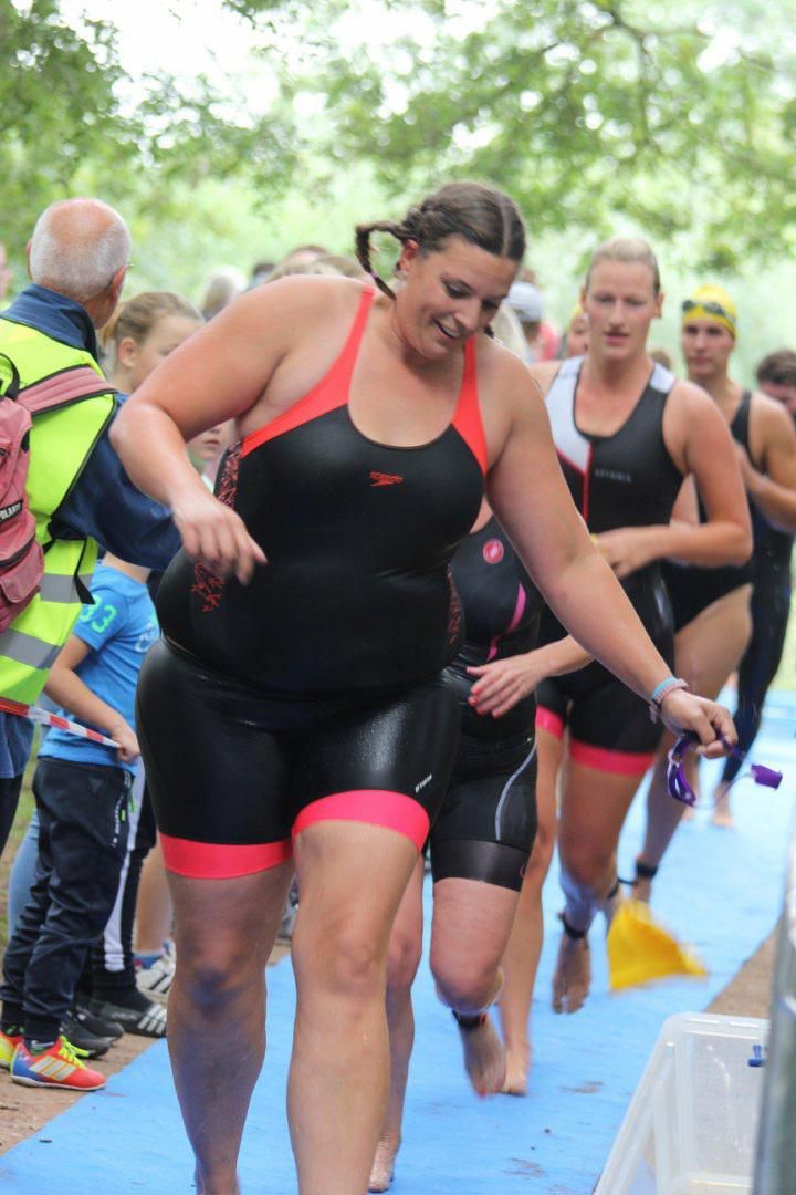 Een groep vrouwen in wetsuits loopt over een blauwe loper.