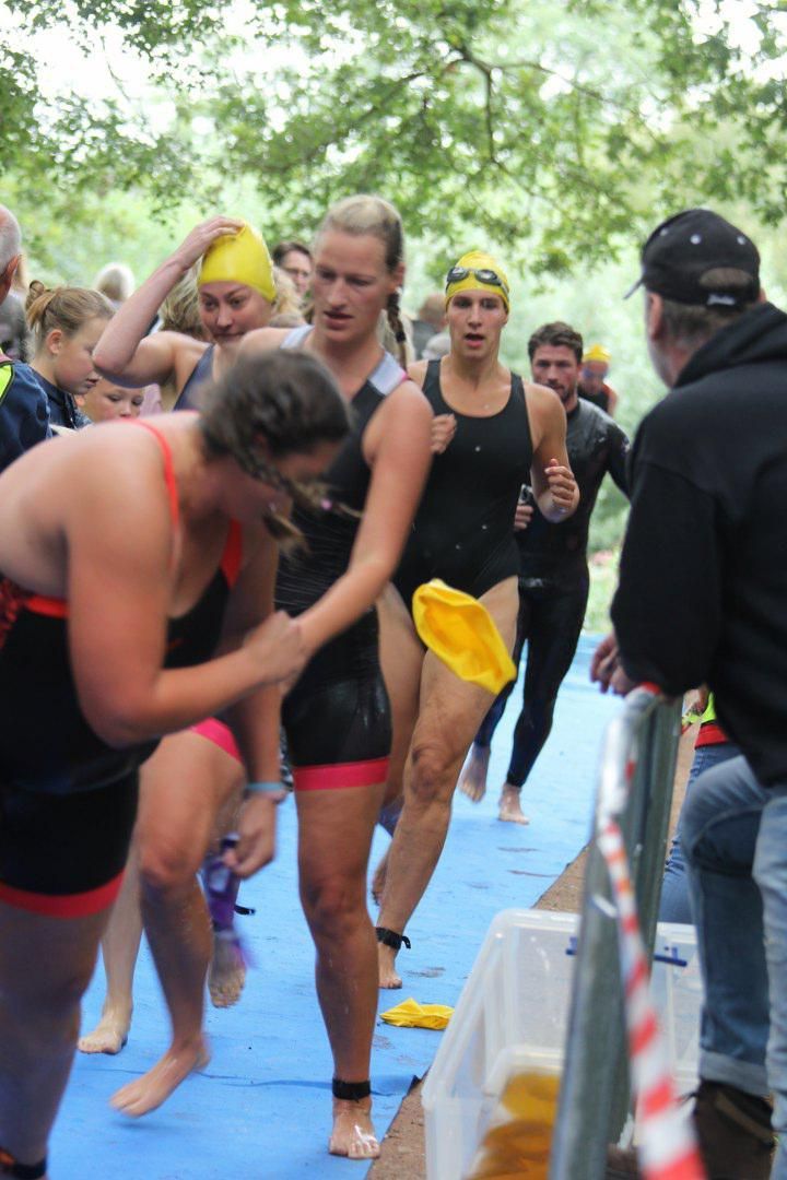Een groep mensen in badpakken loopt op een blauwe mat