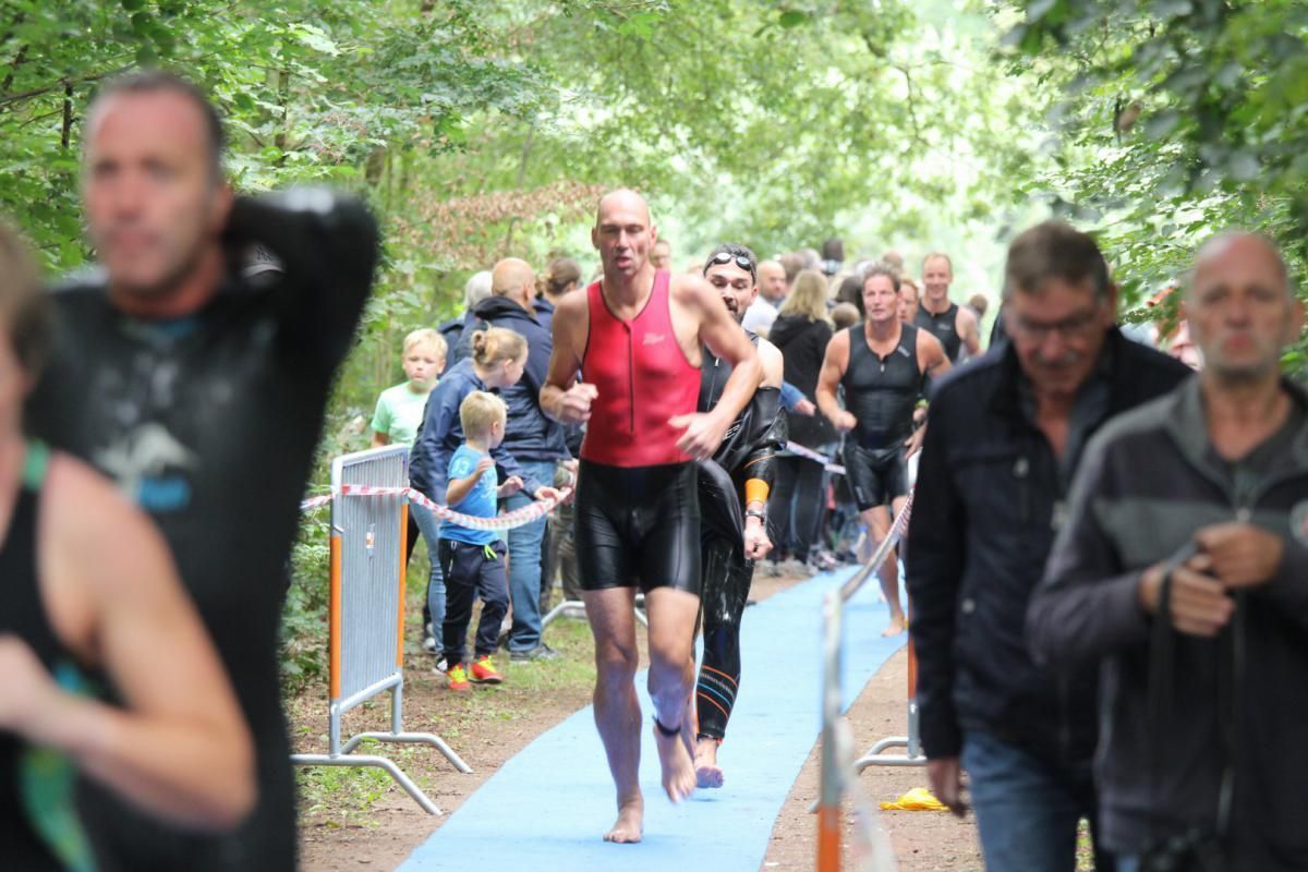 Een groep mensen loopt over een blauw tapijt.