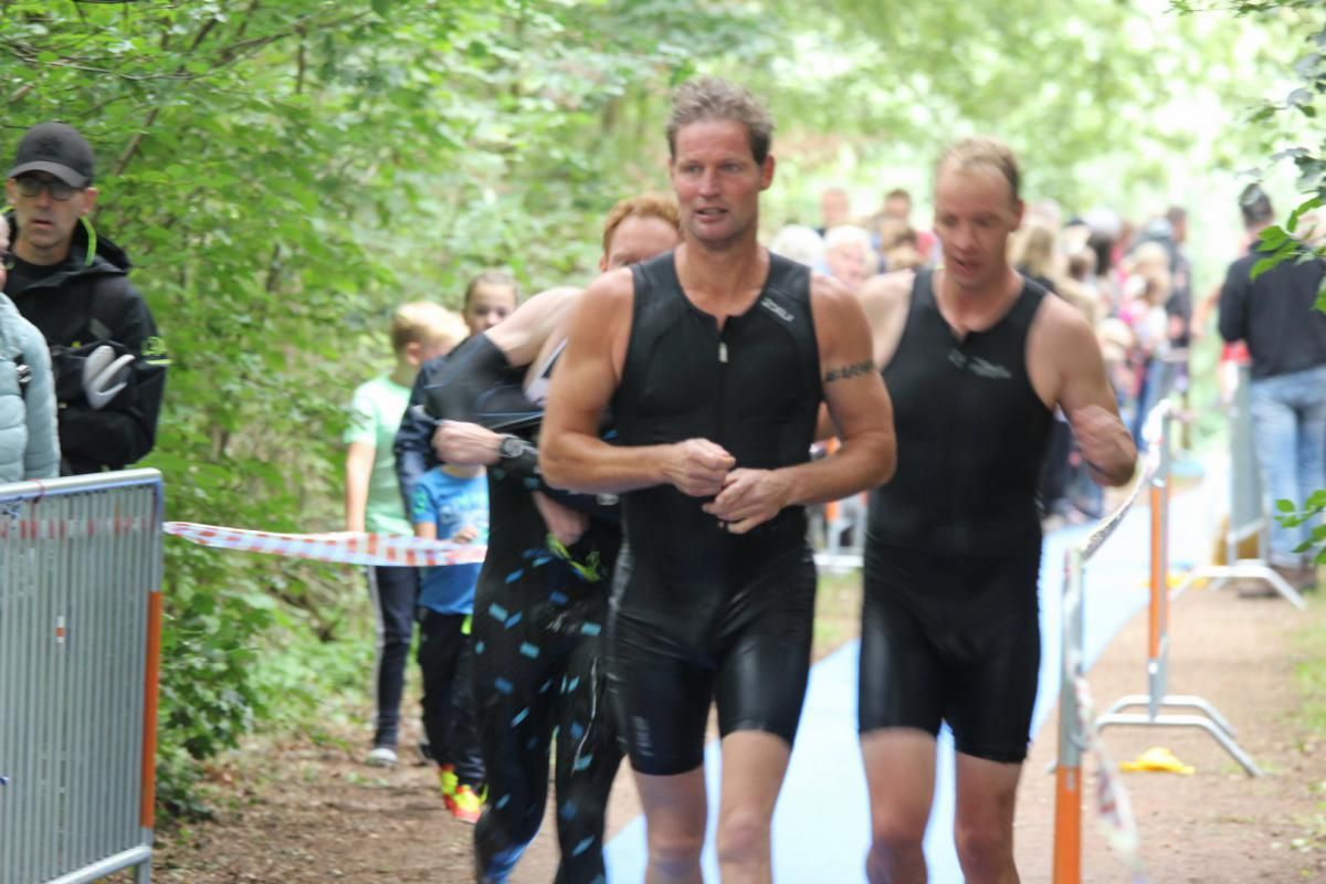 Een groep mannen in wetsuits loopt over een pad.
