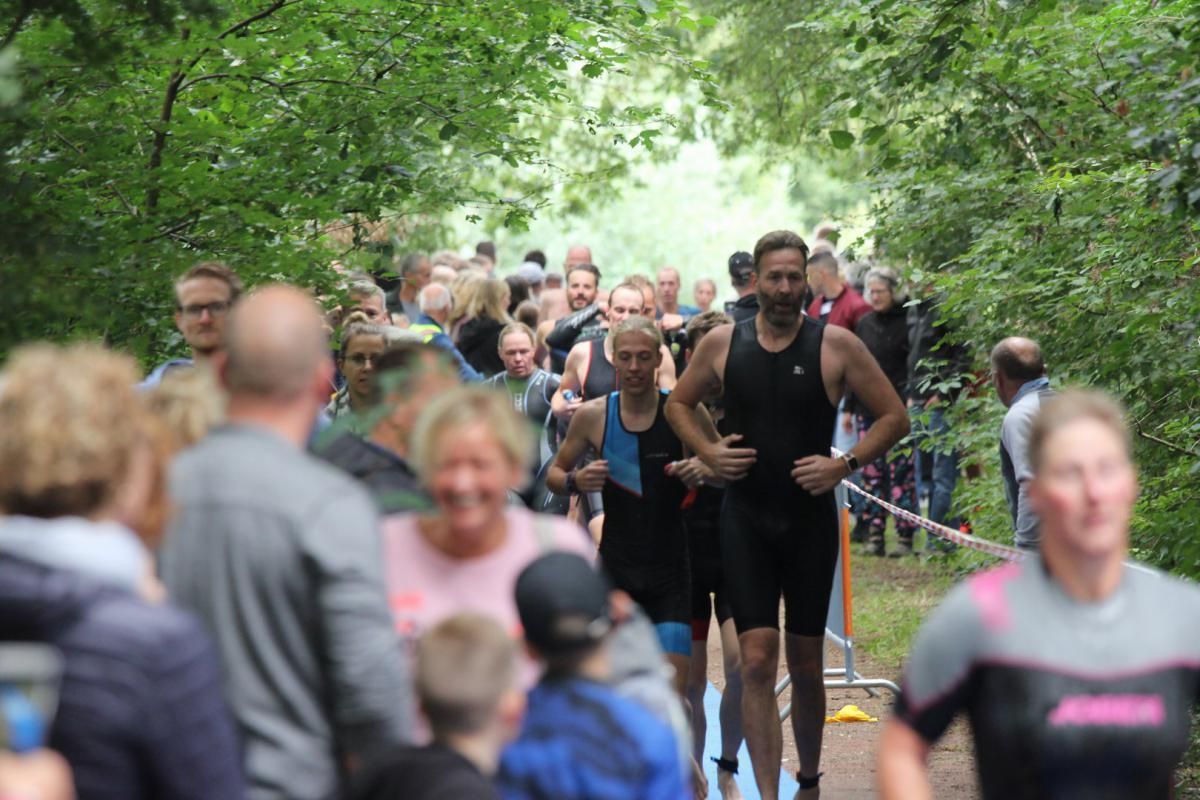 Een groep mensen loopt over een pad in het bos.