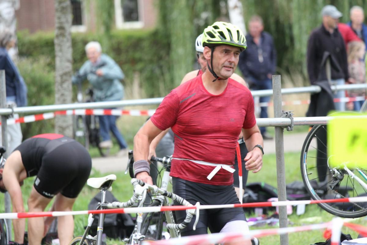 Een man met een helm staat naast een fiets.