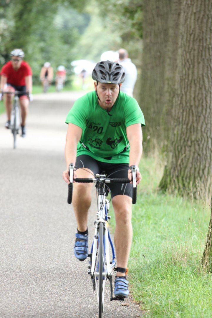 Een man in een groen shirt fietst op een pad