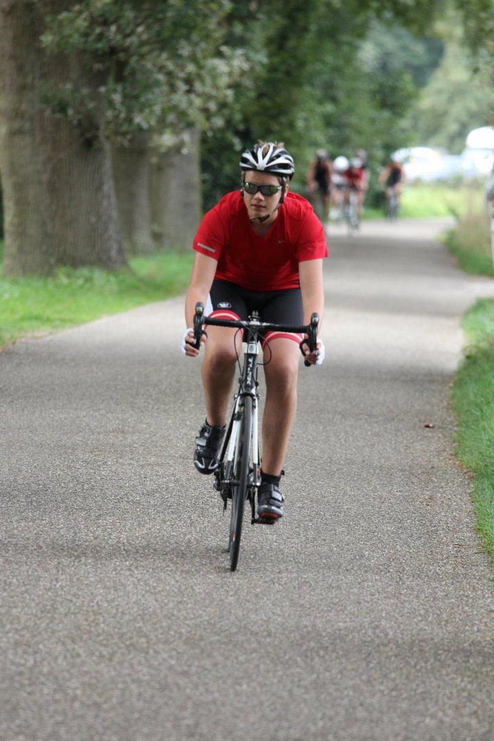 Een man in een rood shirt fietst over een weg.