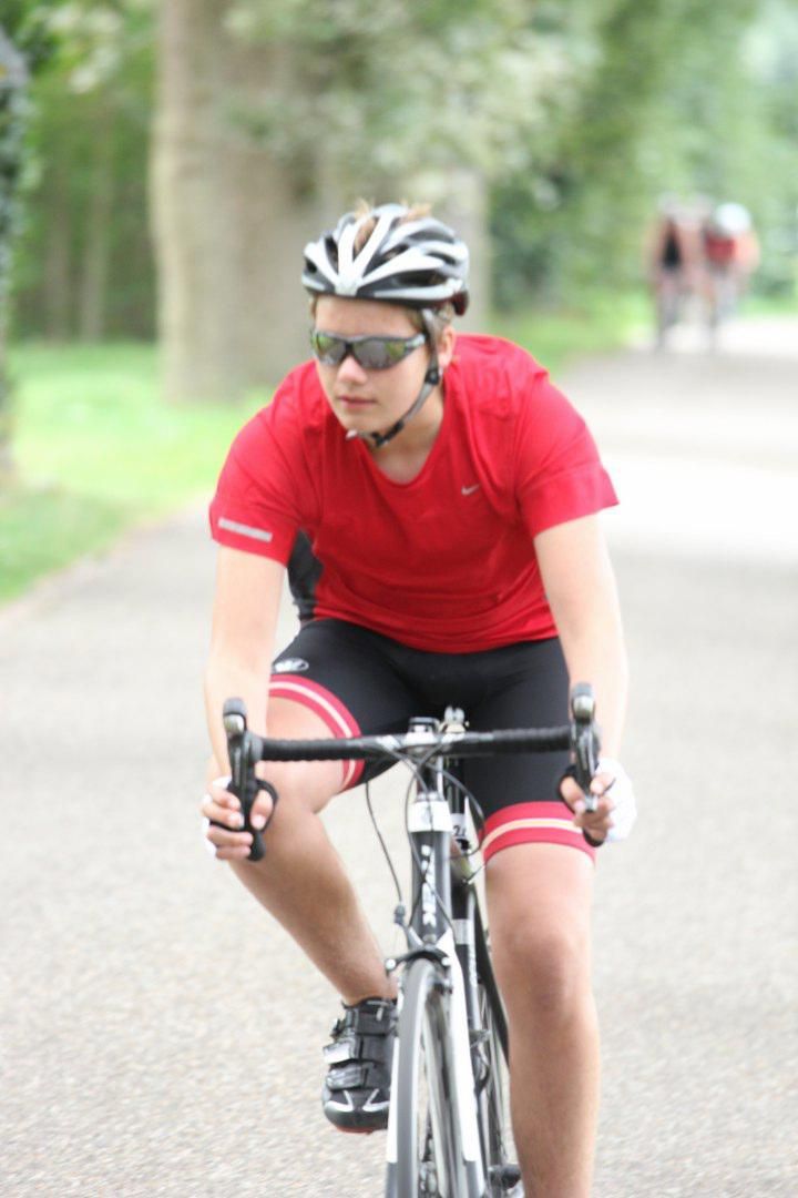 Een persoon met een helm en een zonnebril rijdt op een fiets