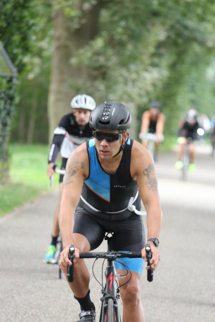 Een man met een helm en een zonnebril fietst over de weg.