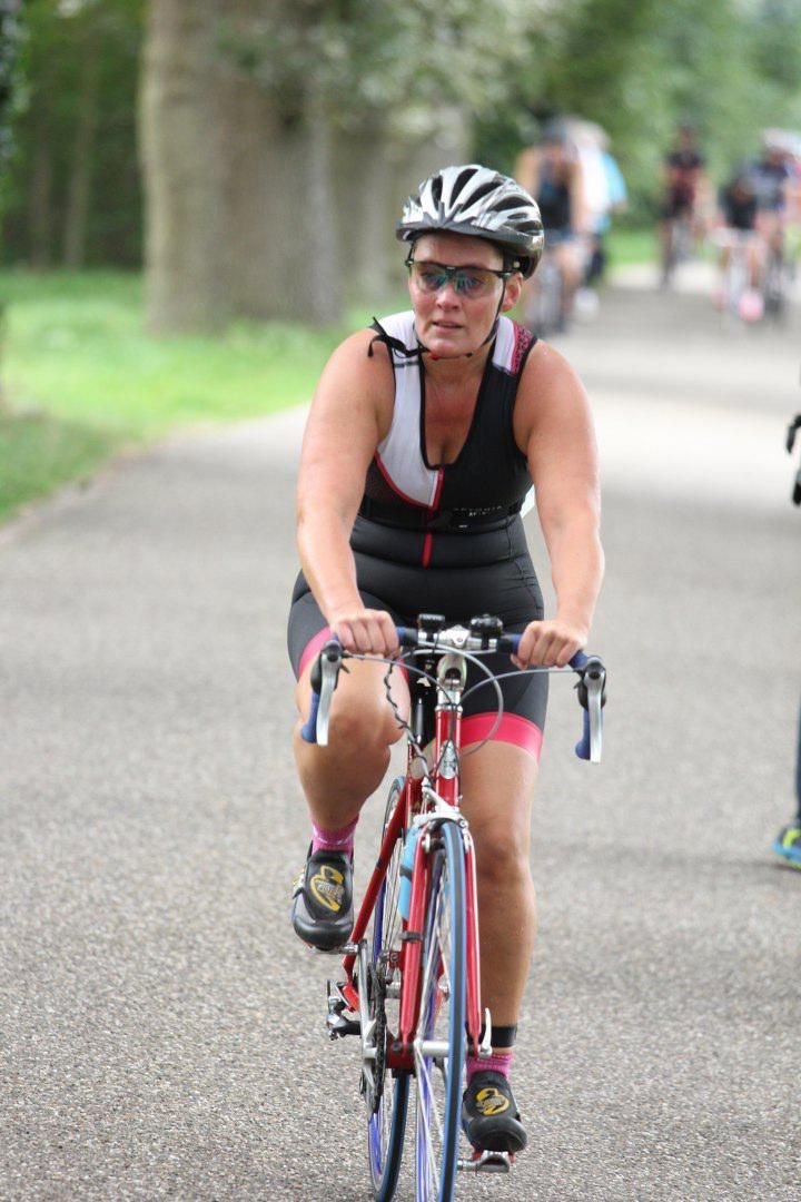 Een vrouw met een helm en een zonnebril fietst op de weg.