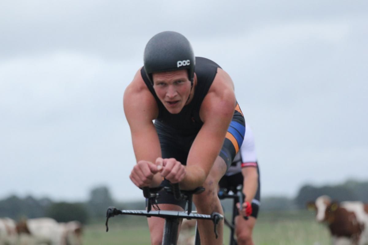 Een man met een helm rijdt op een fiets in een veld