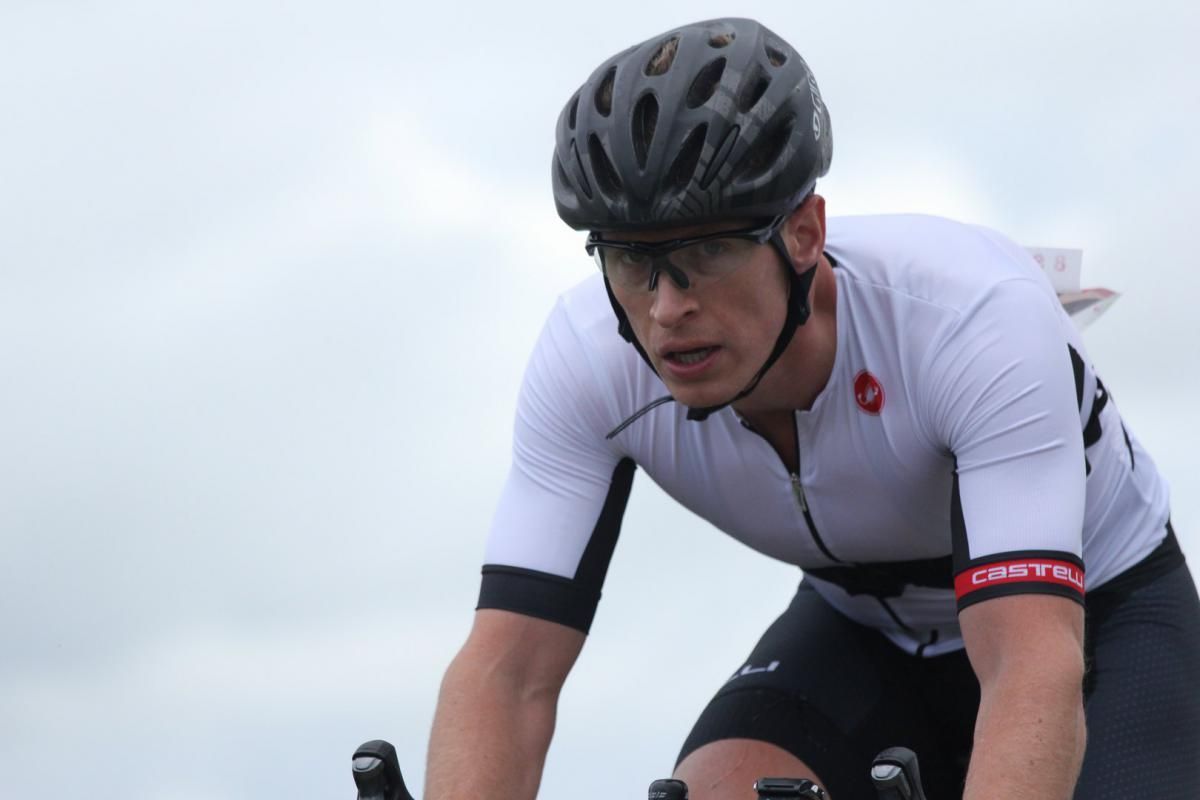 Een man met een helm en een bril rijdt op een fiets