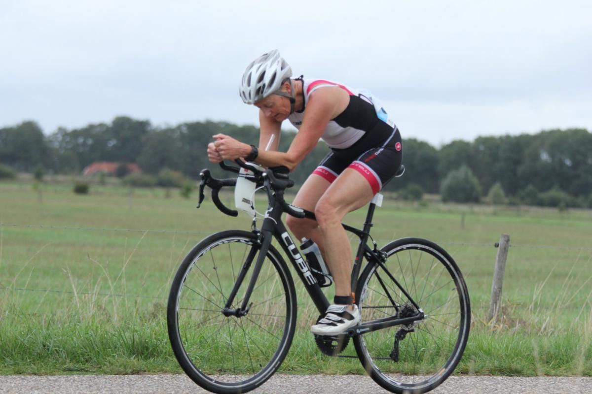 Een vrouw met een helm rijdt op een fiets op een weg