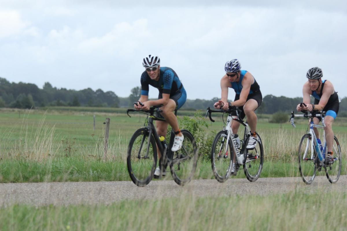 Drie mensen fietsen over een onverharde weg.