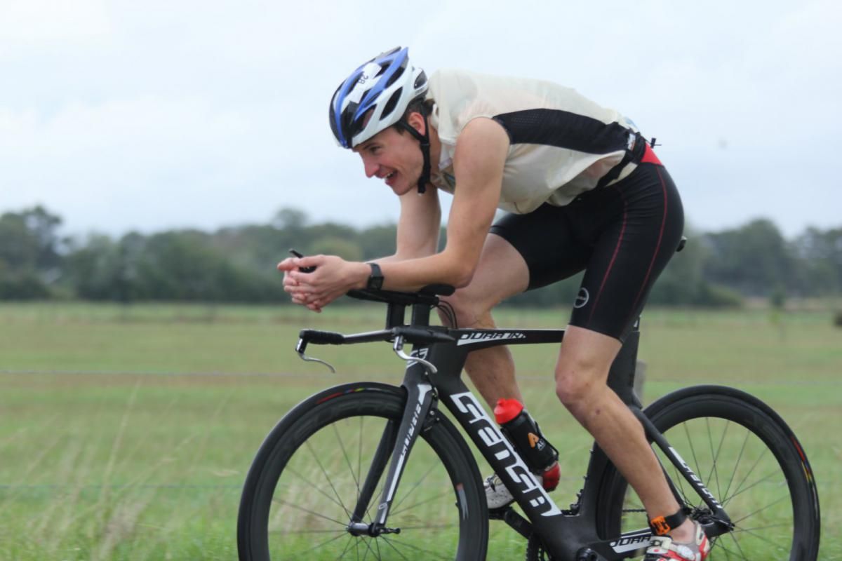 Een man met een helm rijdt op een fiets in een veld.