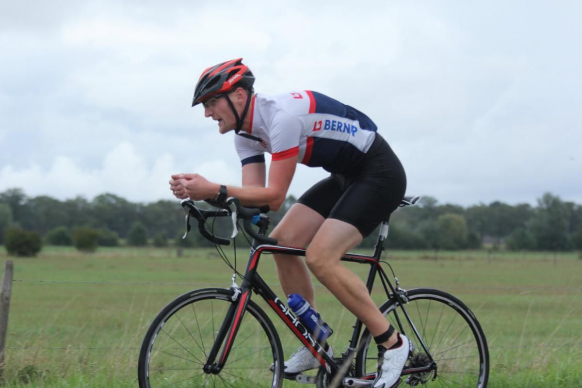 Een man met een helm rijdt op een fiets in een veld