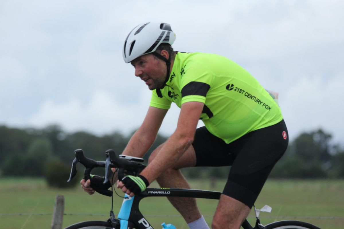Een man met een helm rijdt op een fiets in een veld