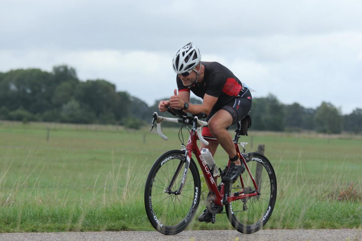 Een man fietst op een weg in een veld.
