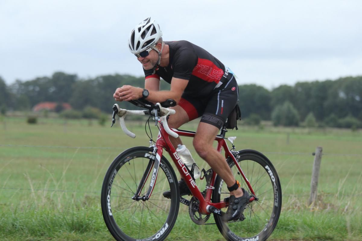 Een man met een helm rijdt op een fiets in een veld