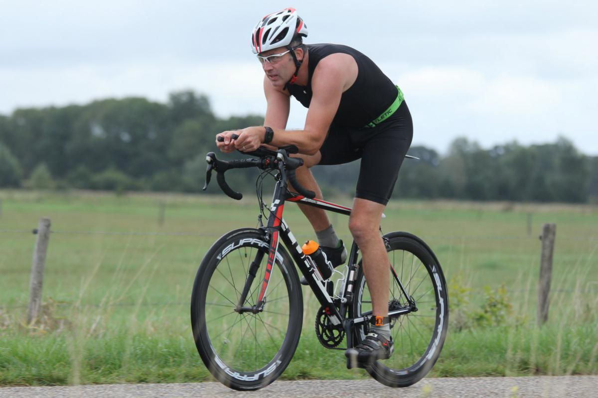 Een man met een helm rijdt op een fiets op de weg.