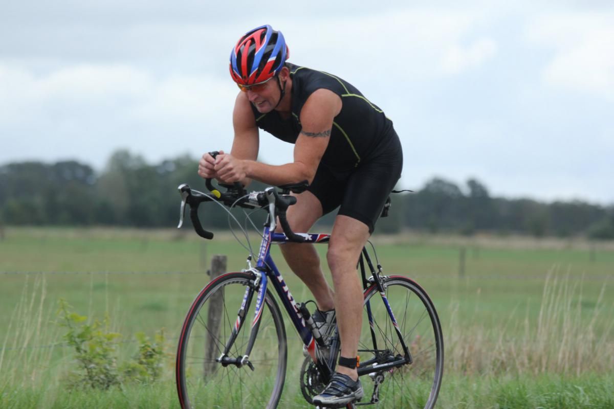 Een man met een helm rijdt op een fiets in een veld