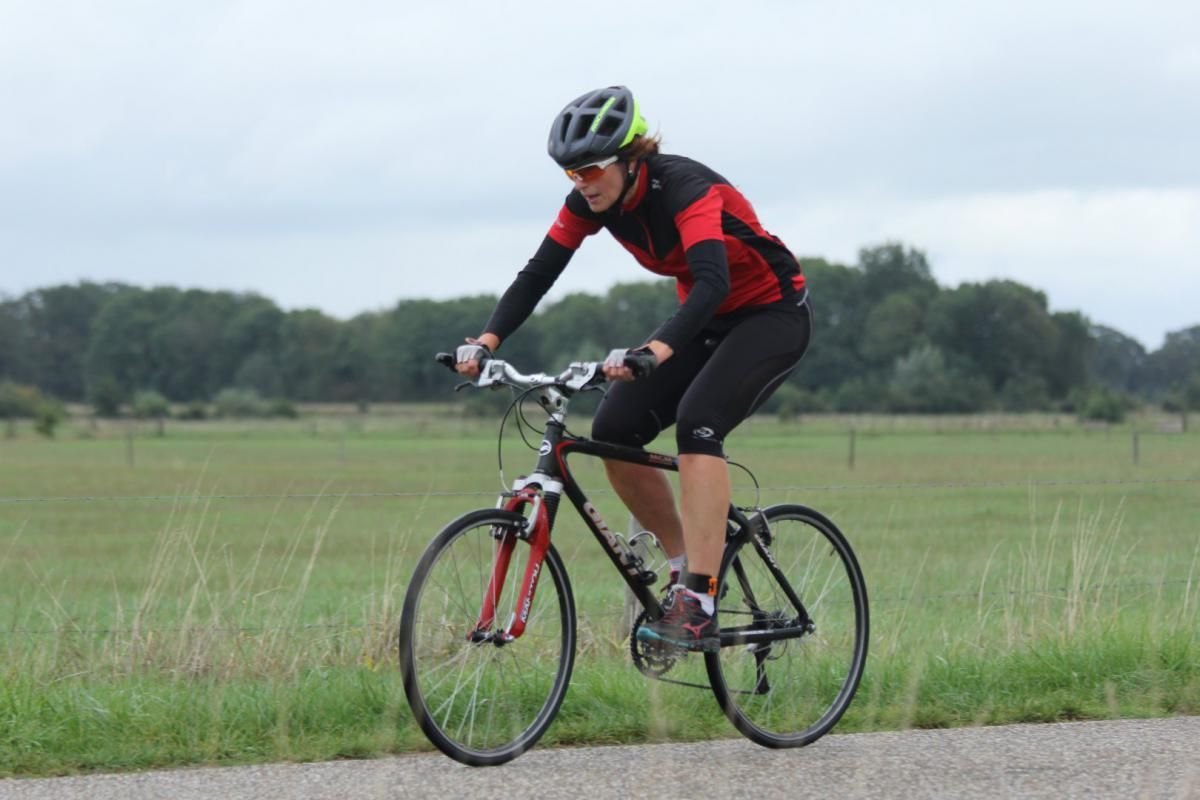 Een persoon die een helm draagt, fietst op een weg