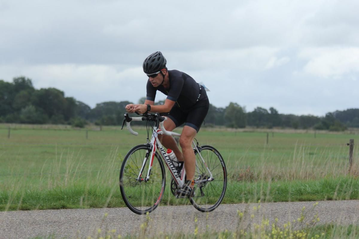 Een man fietst over een onverharde weg.