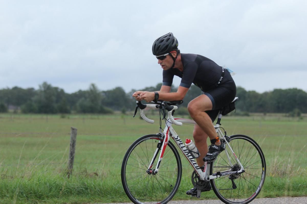 Een man met een helm rijdt op een fiets op de weg.
