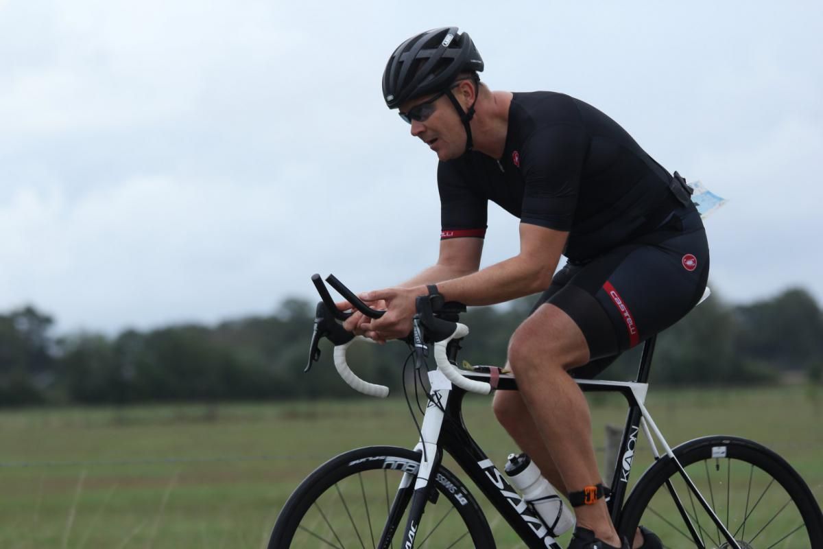 Een man met een helm rijdt op een fiets in een veld