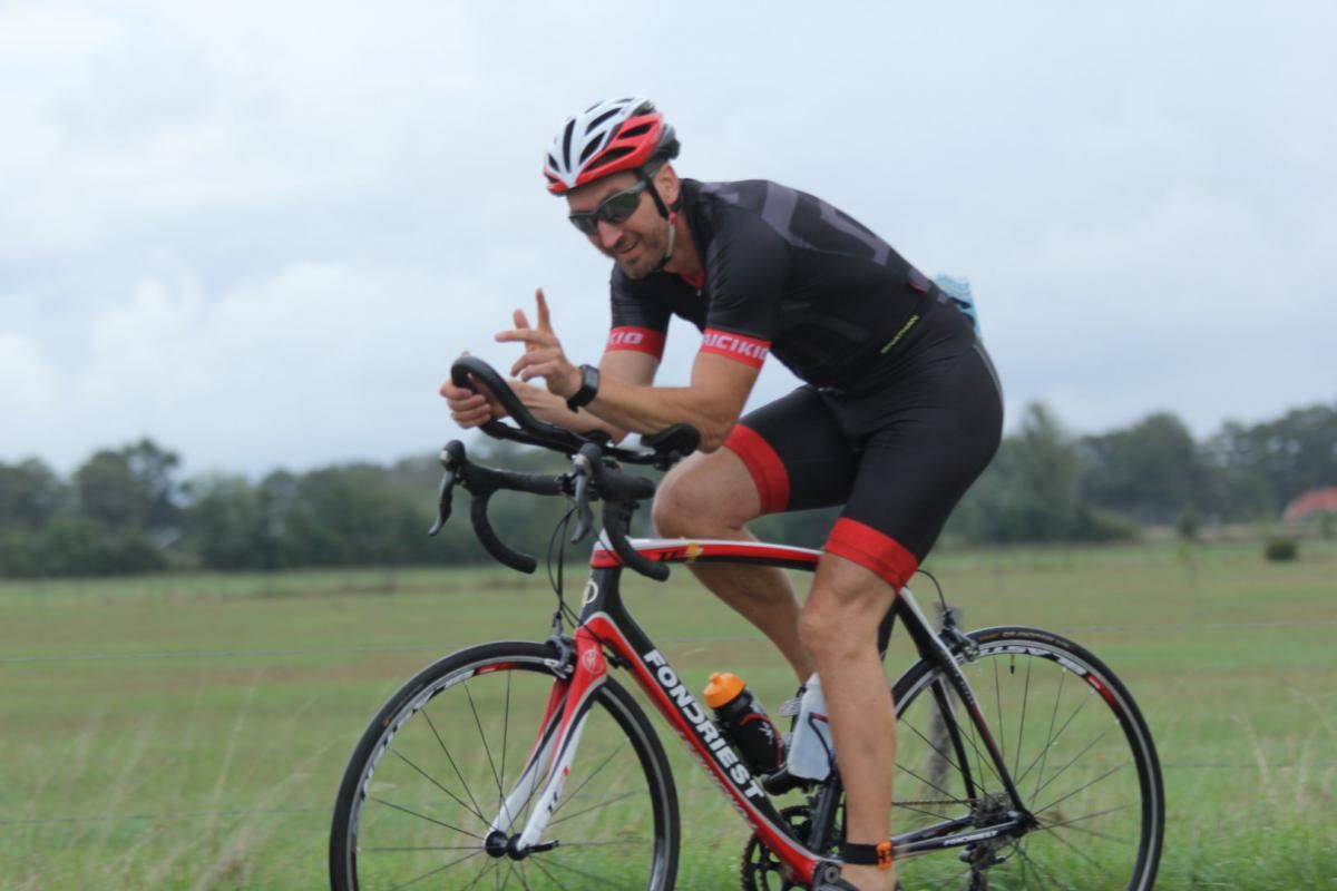 Een man met een helm rijdt op een fiets in een veld