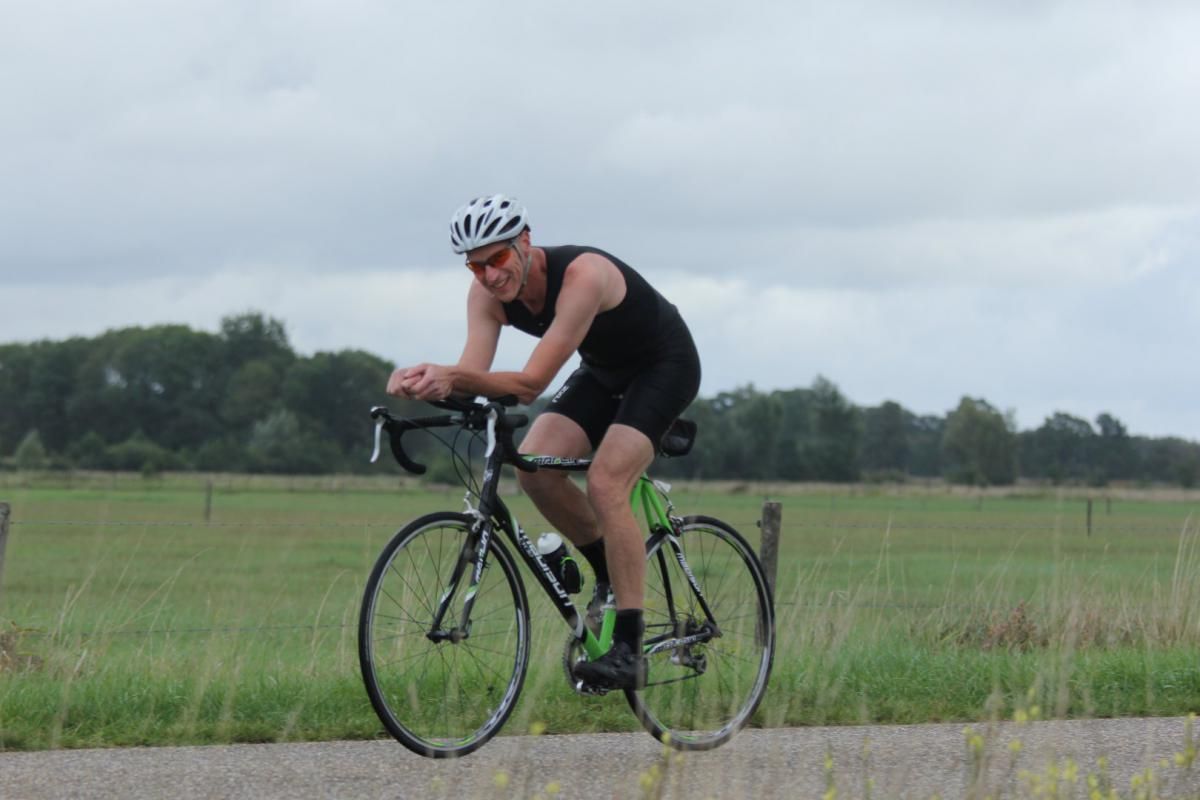 Een man met een helm rijdt op een fiets op een weg