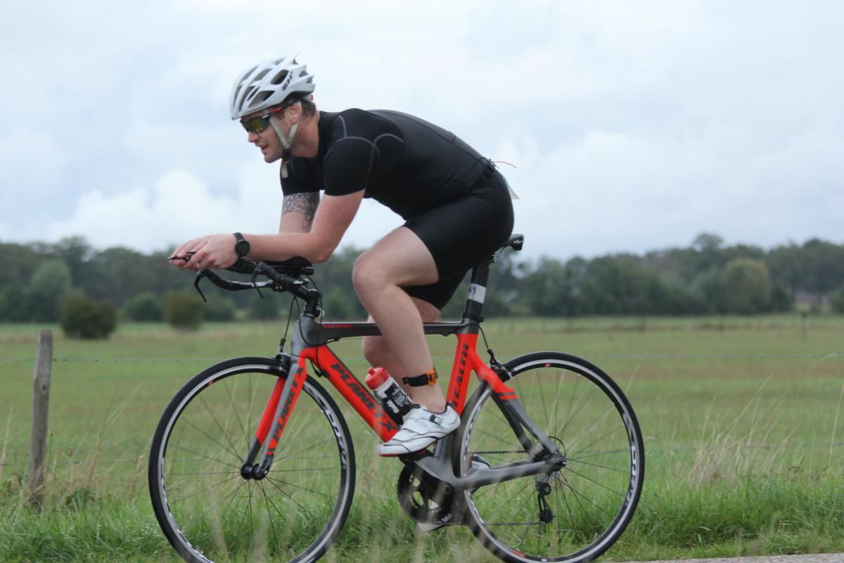 Een man met een helm en een zonnebril rijdt op een rode fiets