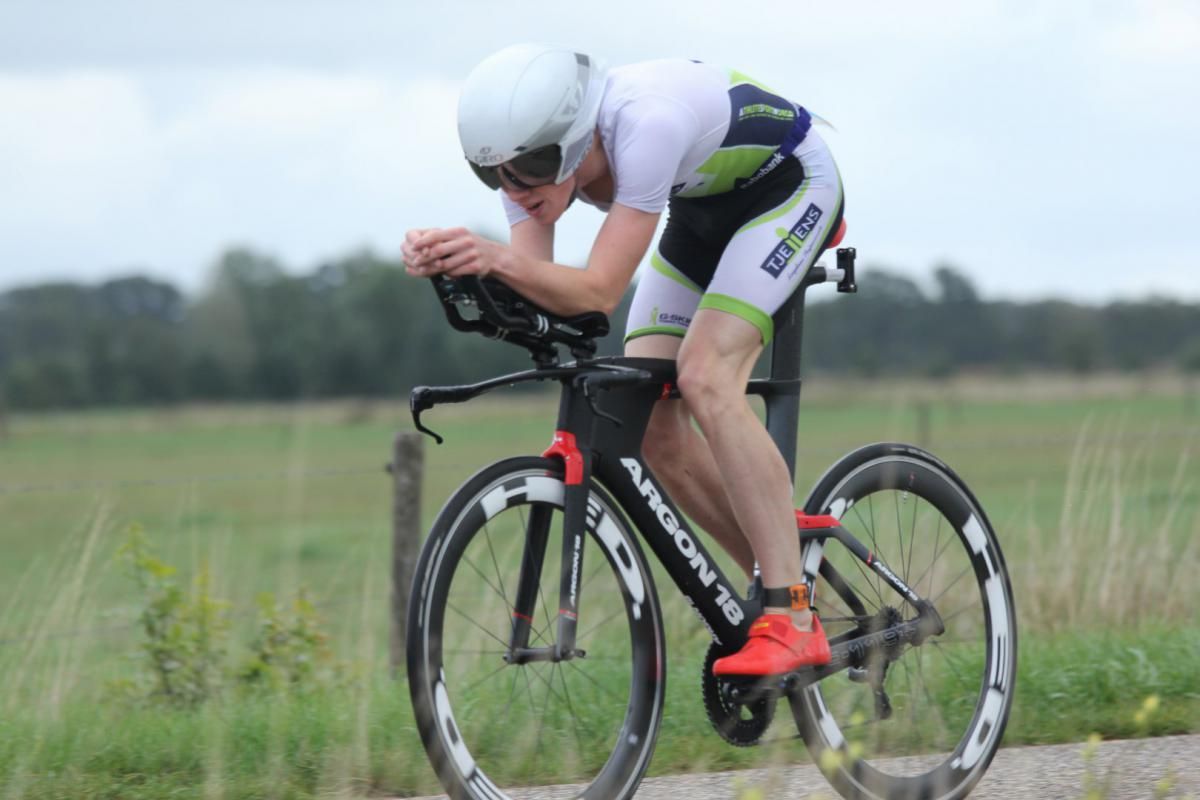Een man fietst op een weg in een veld.