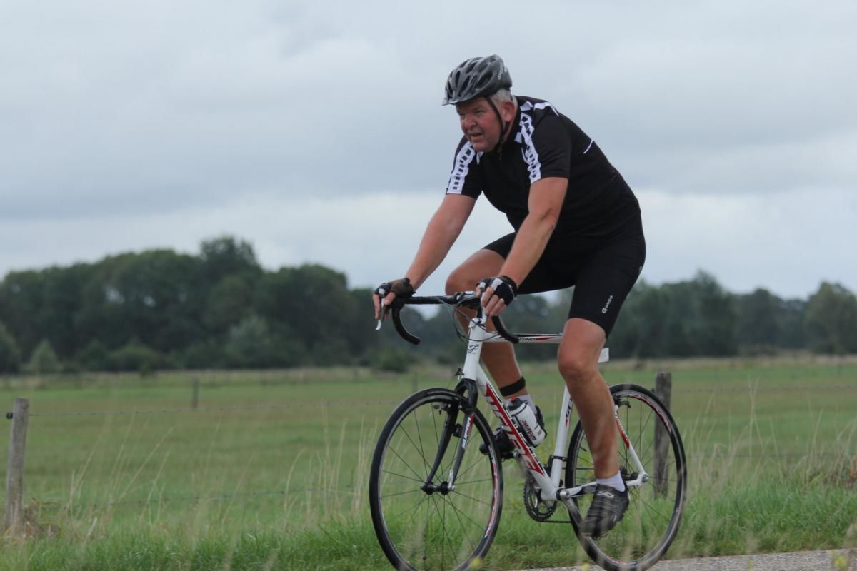 Een man met een helm rijdt op een fiets op een weg