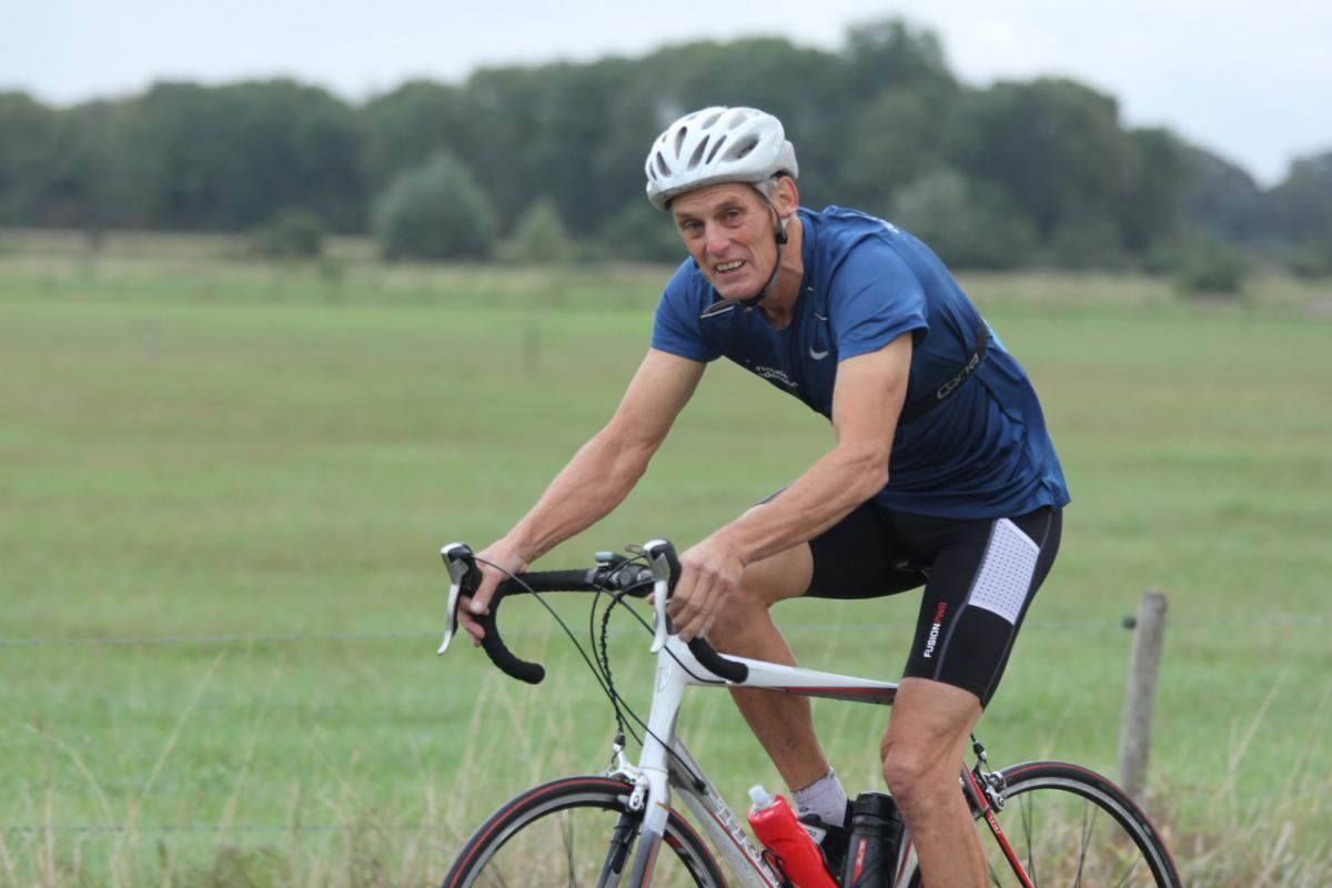 Een man met een helm rijdt op een fiets in een veld.