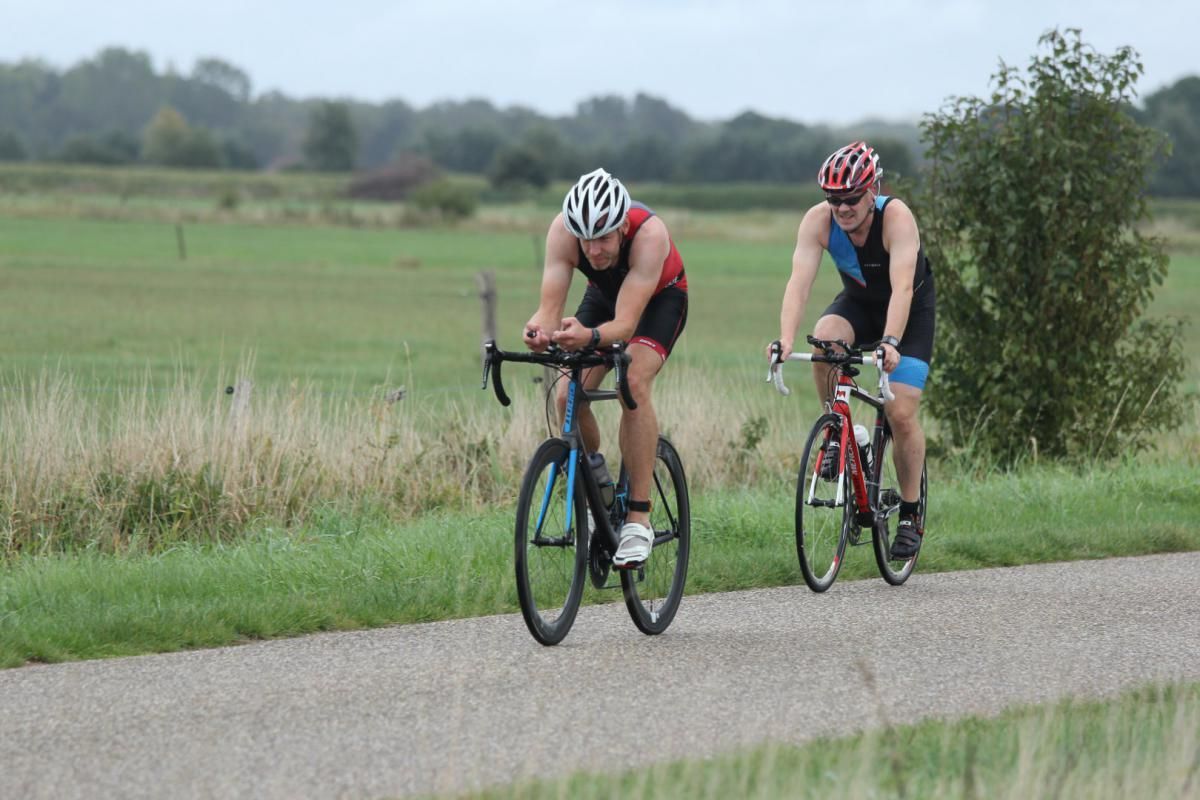 Twee mannen fietsen over een weg.