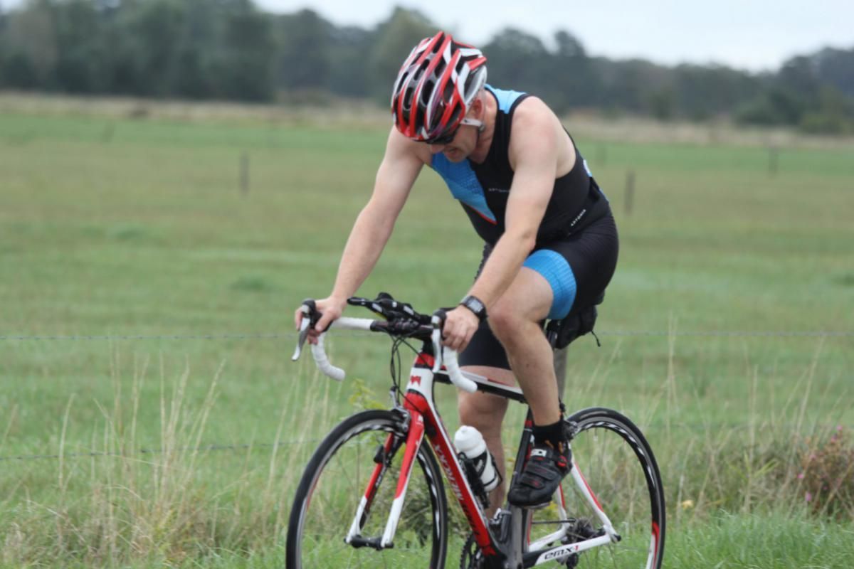 Een man met een helm rijdt op een fiets in een veld.