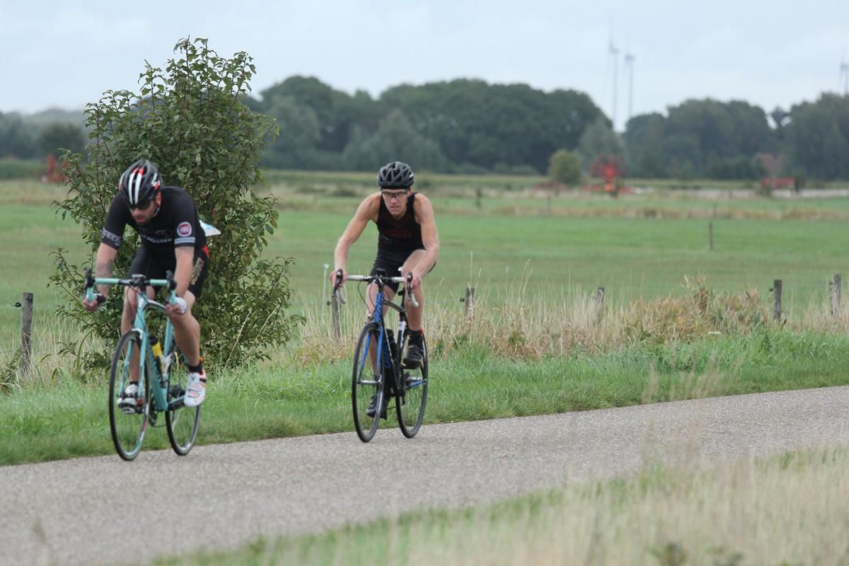 Een man en een vrouw fietsen over een weg.