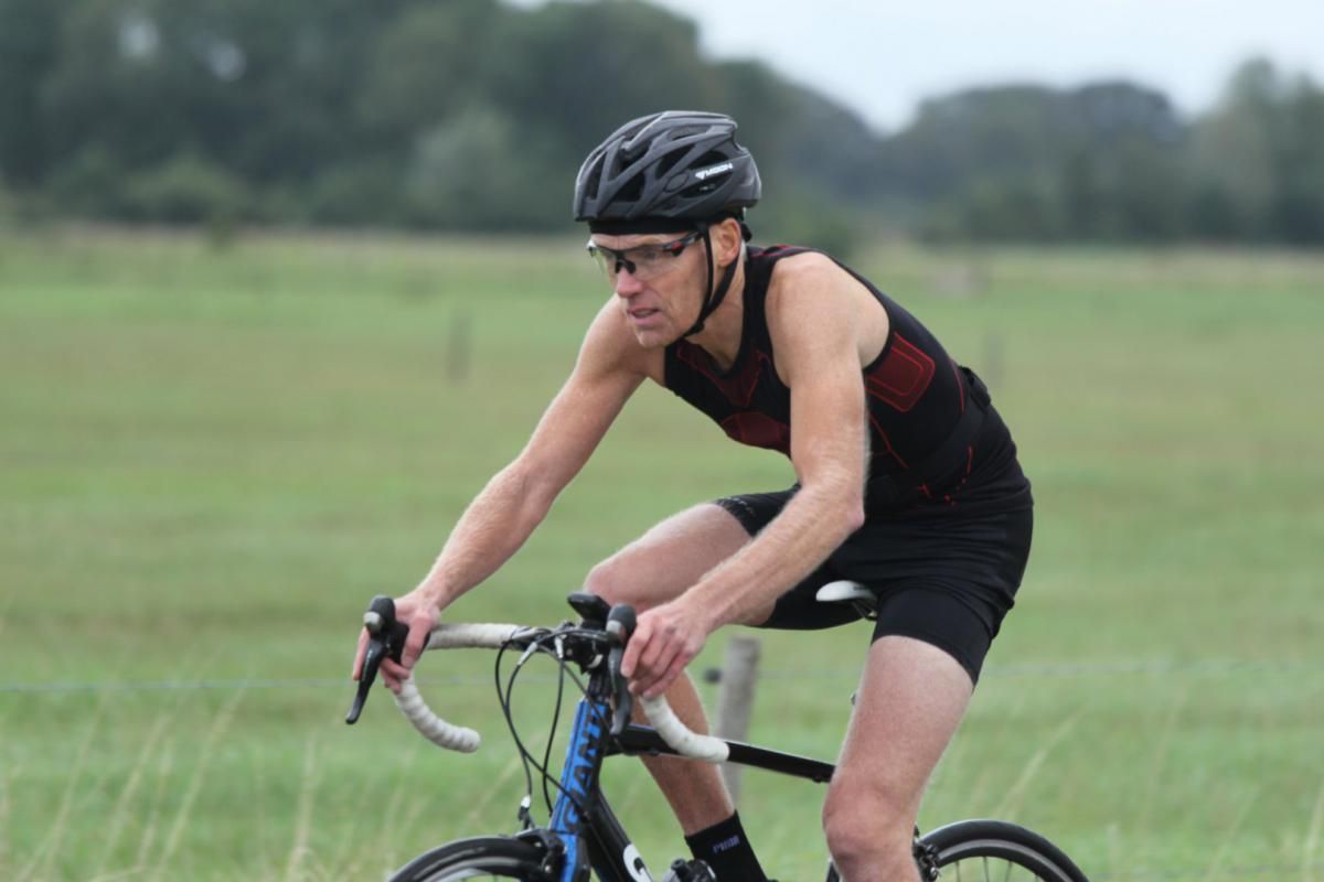 Een man met een helm rijdt op een fiets in een veld.
