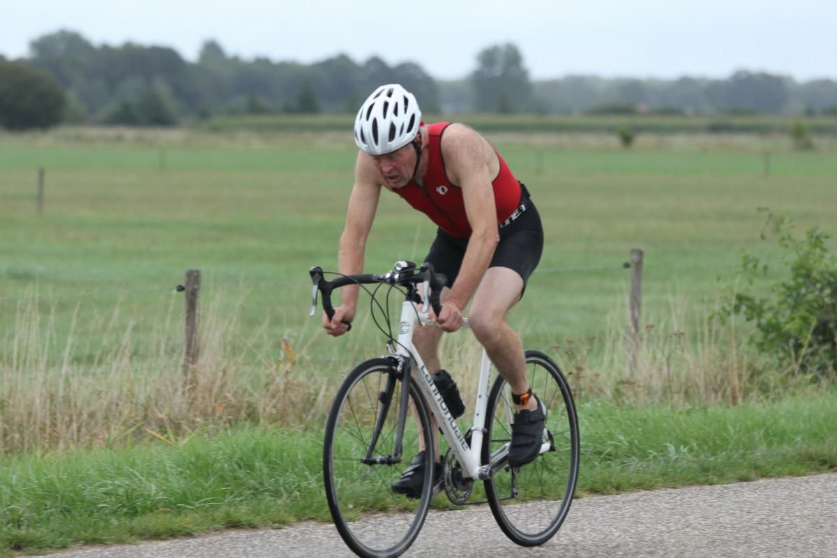 Een man met een helm rijdt op een fiets over de weg.
