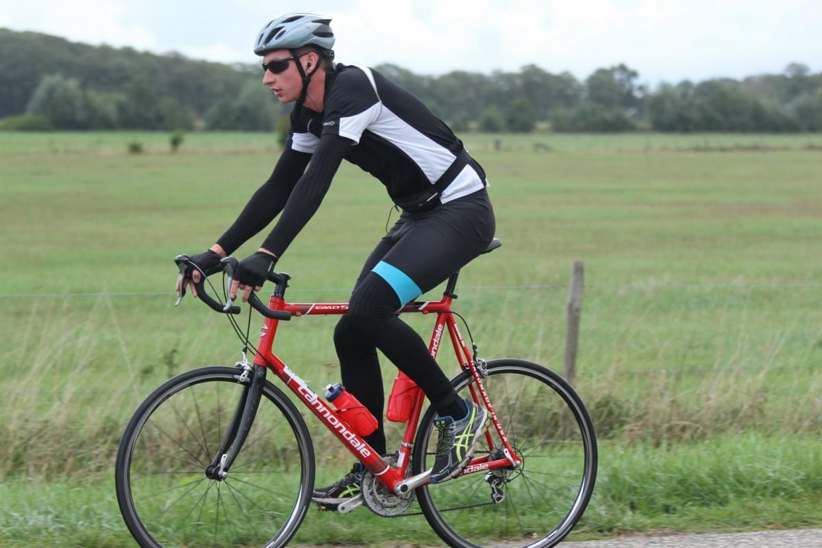 Een man rijdt op een rode fiets op een weg