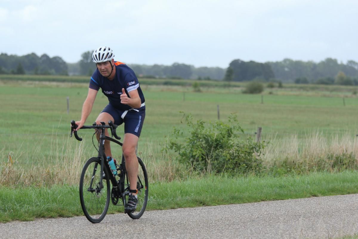 Een man fietst over een onverharde weg.