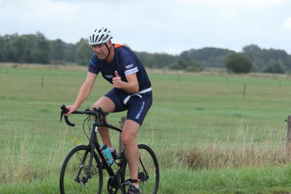 Een man fietst in een veld en steekt zijn duim omhoog